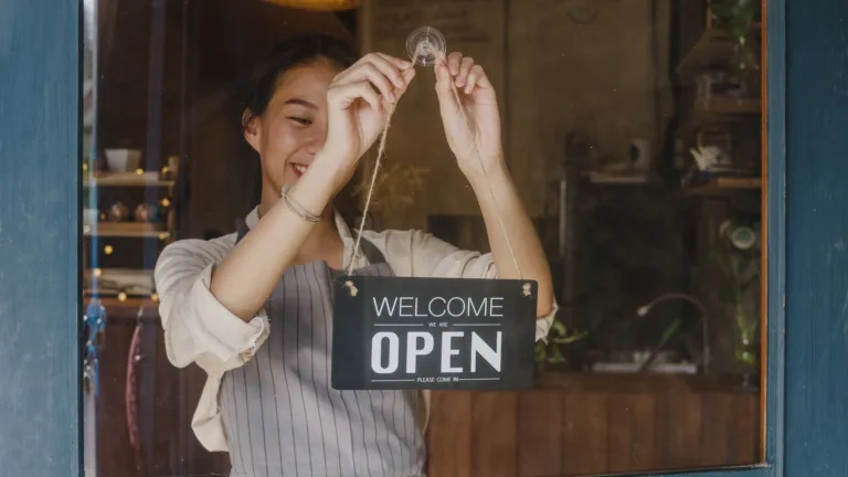 photo of business owner changing a sign from closed to open sign