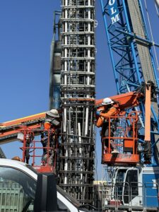 two construction workers splice a Caterpillar Shaft D-Wall GFRP rebar cage