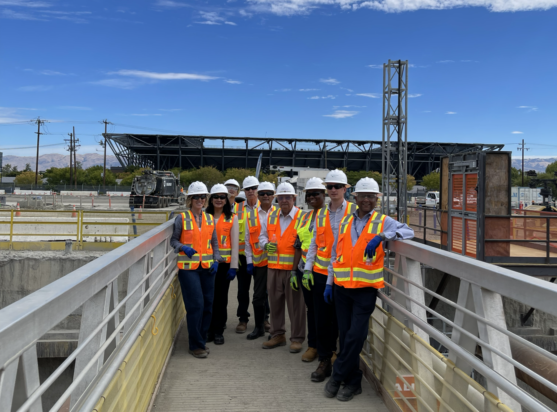 A group of people in construction PPE pose at a construction site