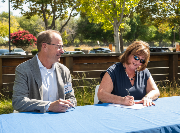 Woman and Man sit a table and sign a document