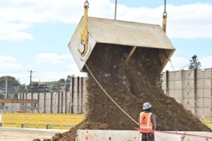 Dirt being dumped at a construction site while a construction worker looks on