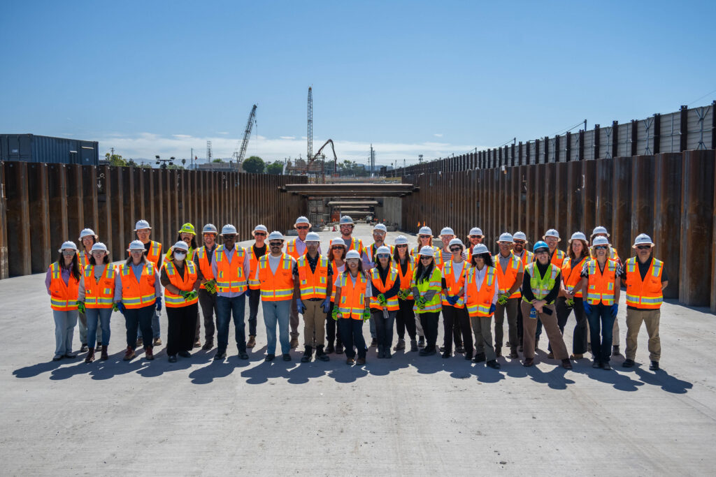 A large group of people in construction gear pose for a photo at a construction site