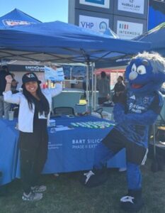a woman and a sports mascot cheer in front of a table